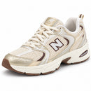 New Balance 530 Off/Dourado/Café, vista frontal em três quartos com a ponta para a esquerda, fundo branco