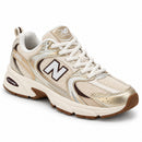 New Balance 530 Off/Dourado/Café, vista frontal em três quartos com a ponta para a direita, fundo branco